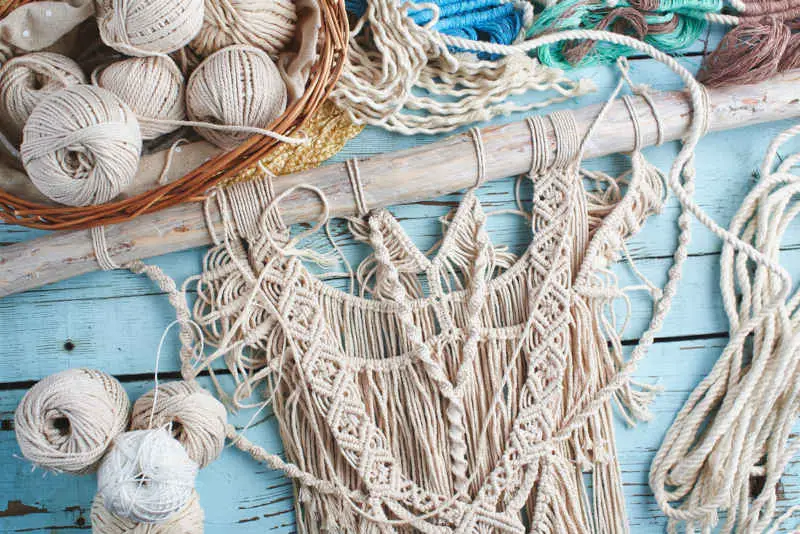 Handmade macrame braiding, background thread on a wooden Board top view handmade gift ideas - macrame decorations